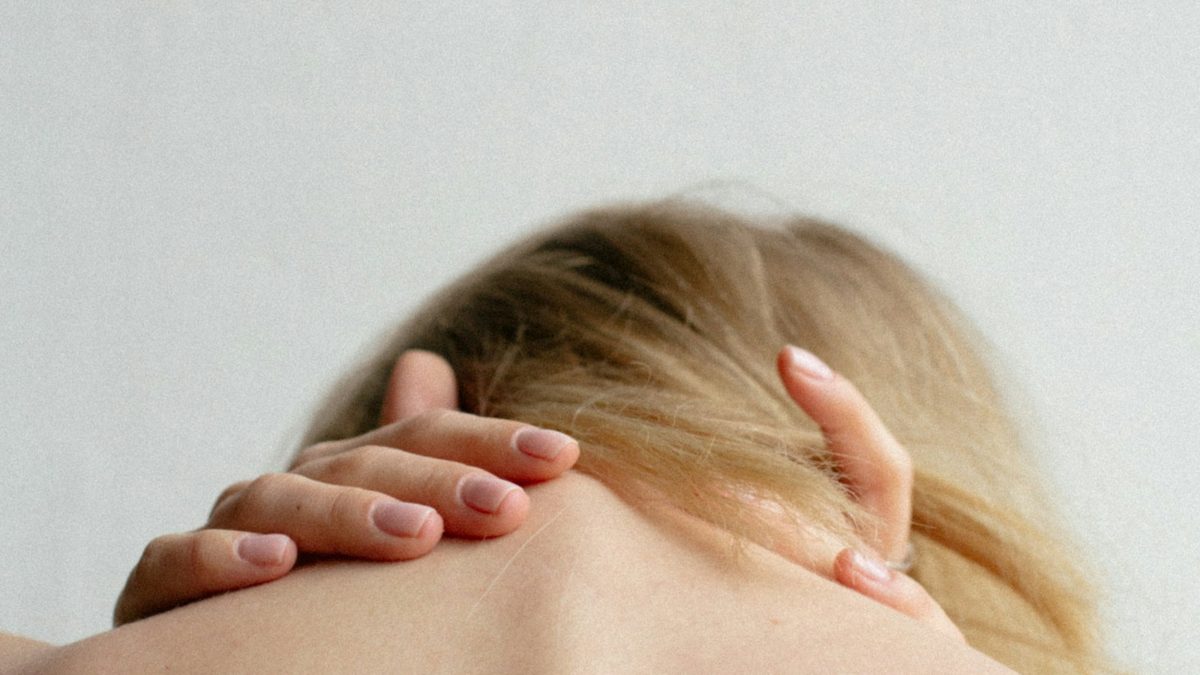 Vrouw met handen in haar gespannen nek