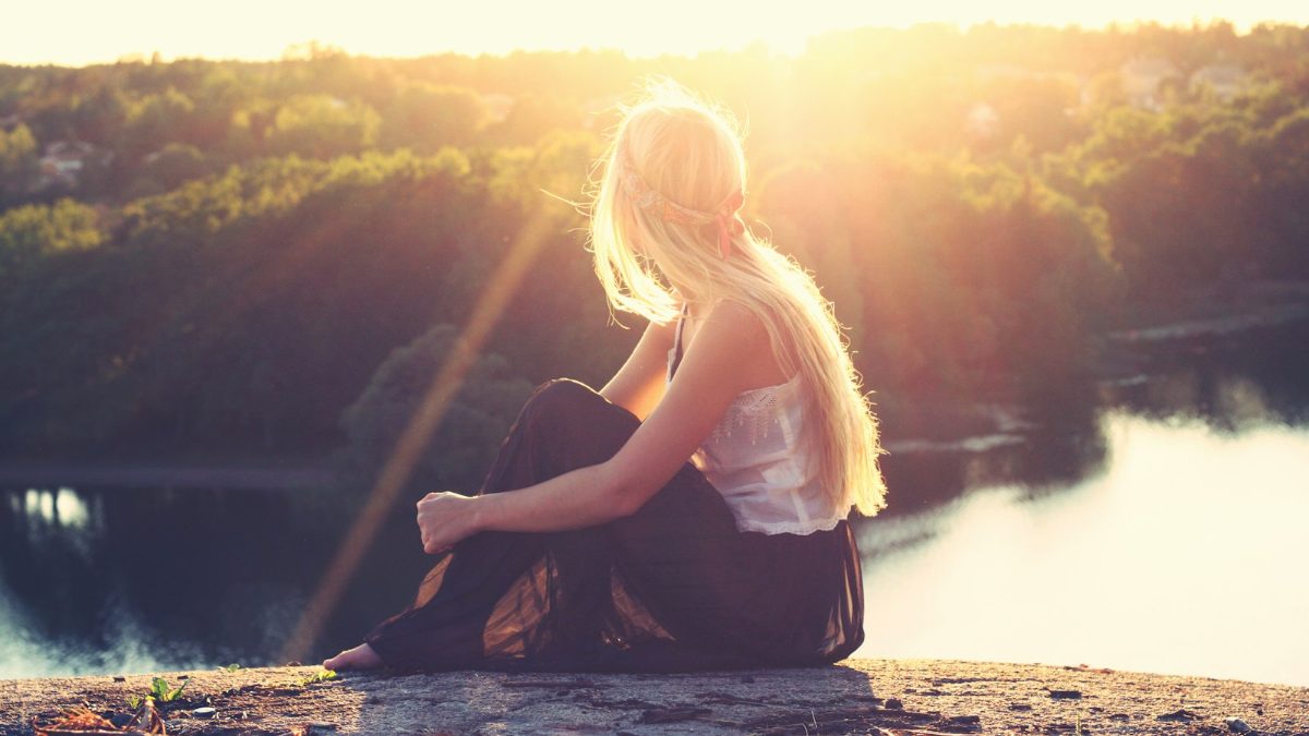 Vrouw komt tot rust aan een meer in de zon